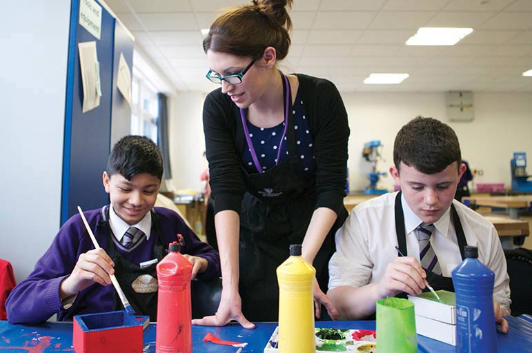 Teacher in classroom with students painting