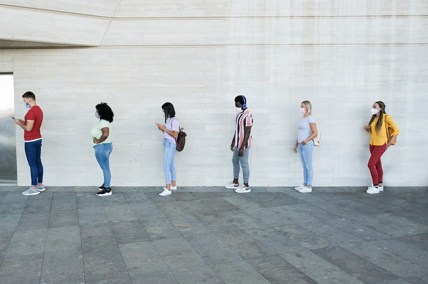 People standing in a queue two metres apart wearing masks