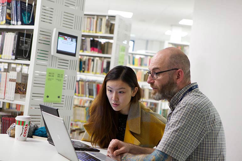 Teacher and student using laptop