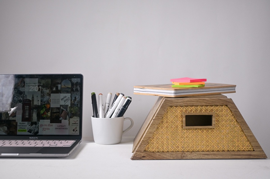 A typical student desk with a laptop and pens and a storage box with some books and folders on top