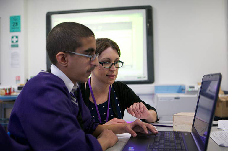 Teacher helping student on laptop