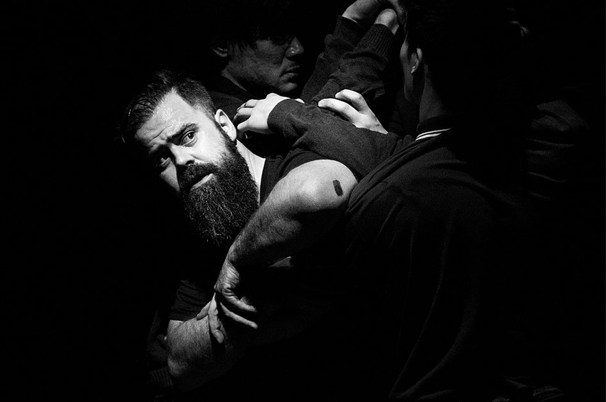 A black and white photo of several men wrestling with eachother.