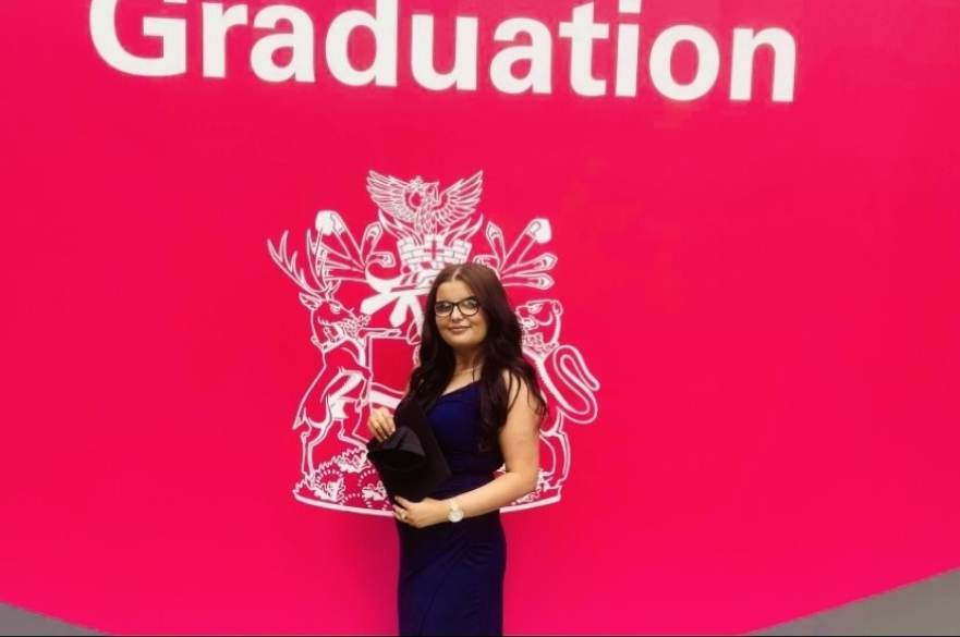 Georgia posing in front of the NTU graduation sign