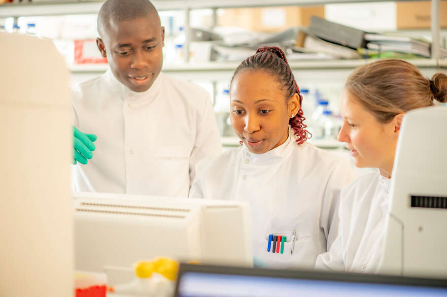 Three researchers looking at equipment in a lab