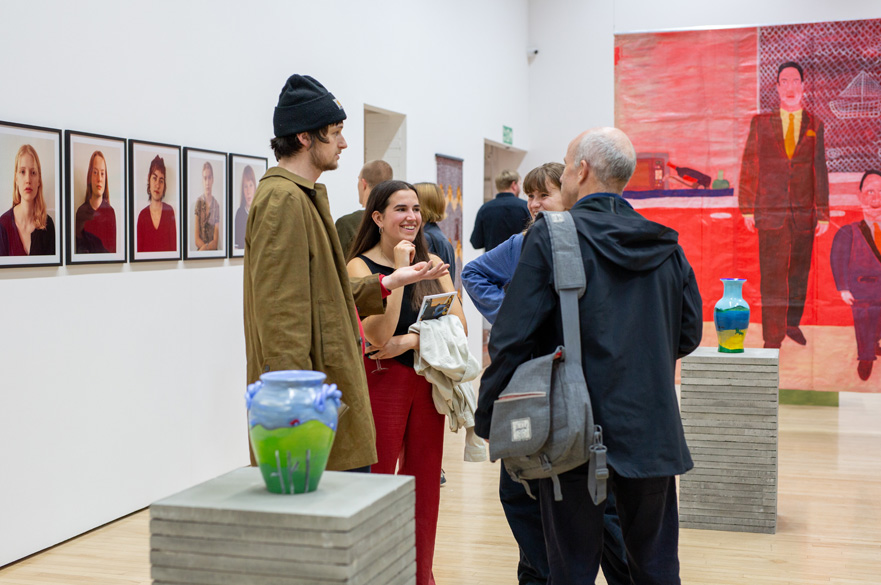 Four people standing in a gallery smiling and chatting to eachother