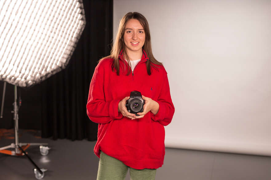 Student holding camera in Bonington photo studio