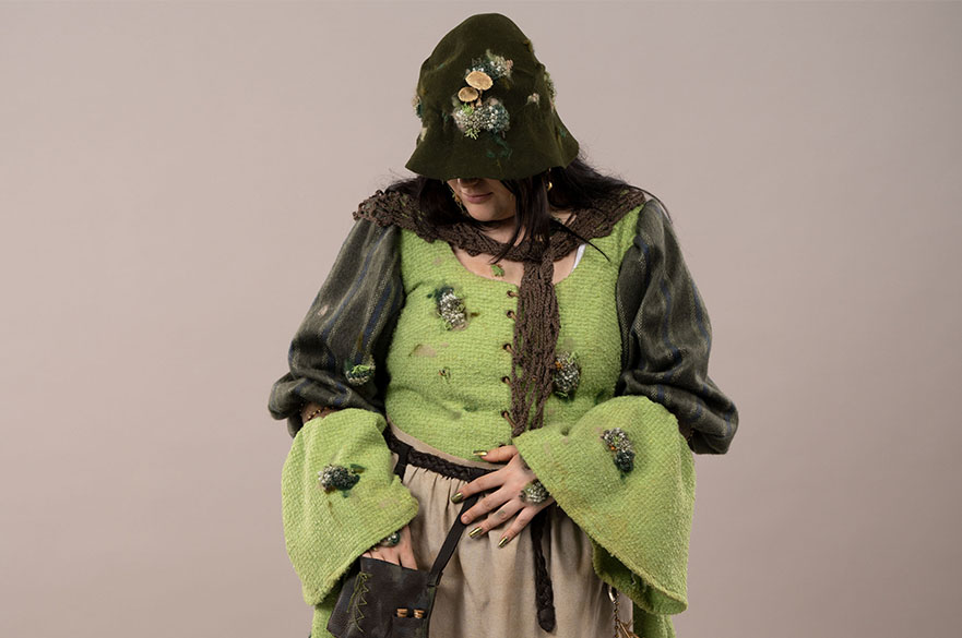 Person in a green knitted costume with a dark green hood