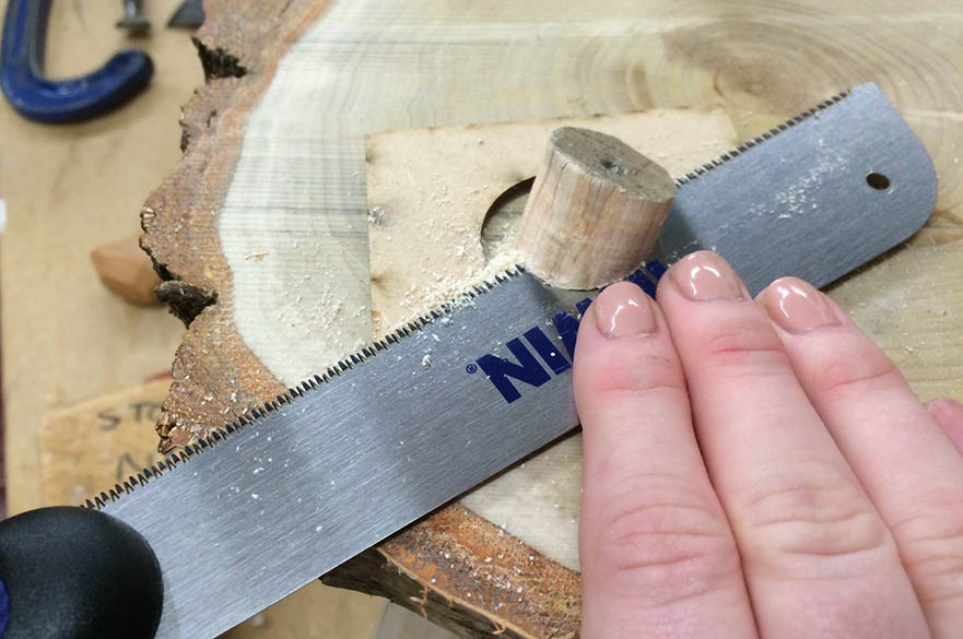 A hand sawing through wood.