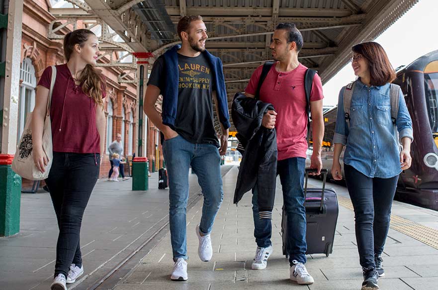 Four students walking along the platform at Nottingham train station