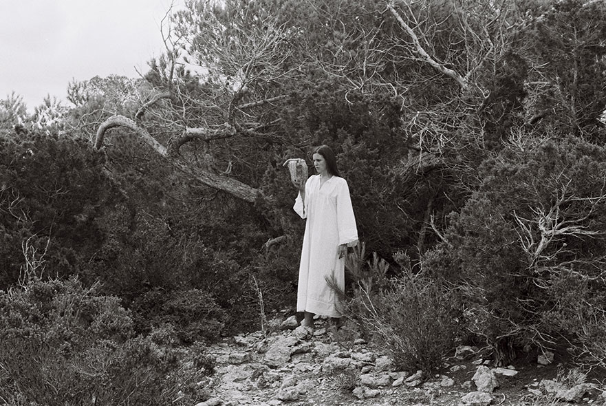 A black and white photo of a woman in a wood holding an animal skull