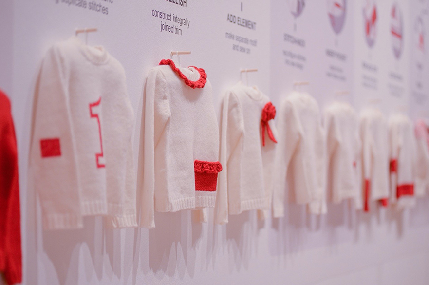 Knitted cream jumpers with red detailing are being displayed at the Reknit Revolution art exhibition. 