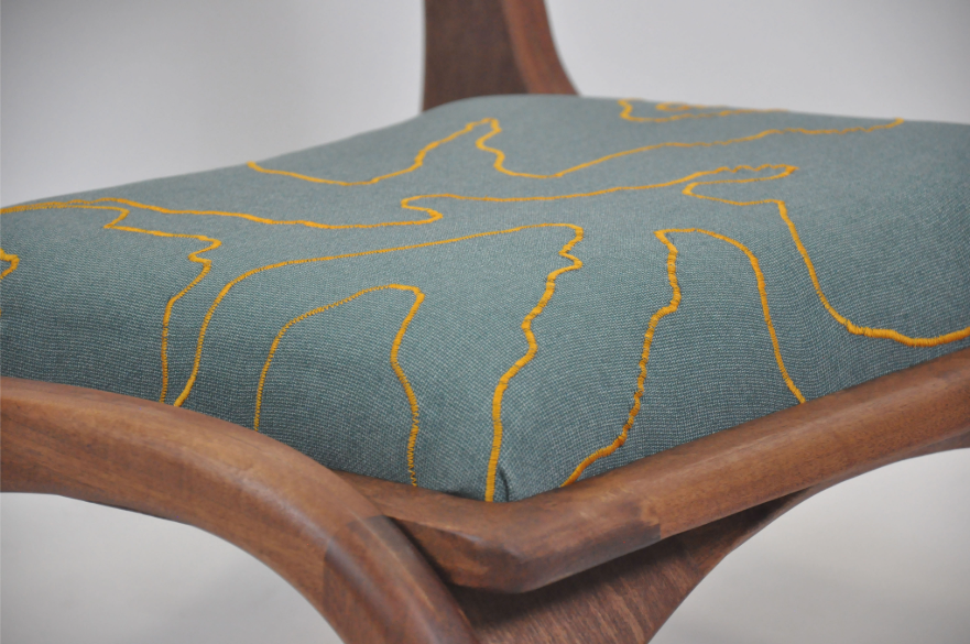 A close up detail of a chair, showing the joinery and upholstery.