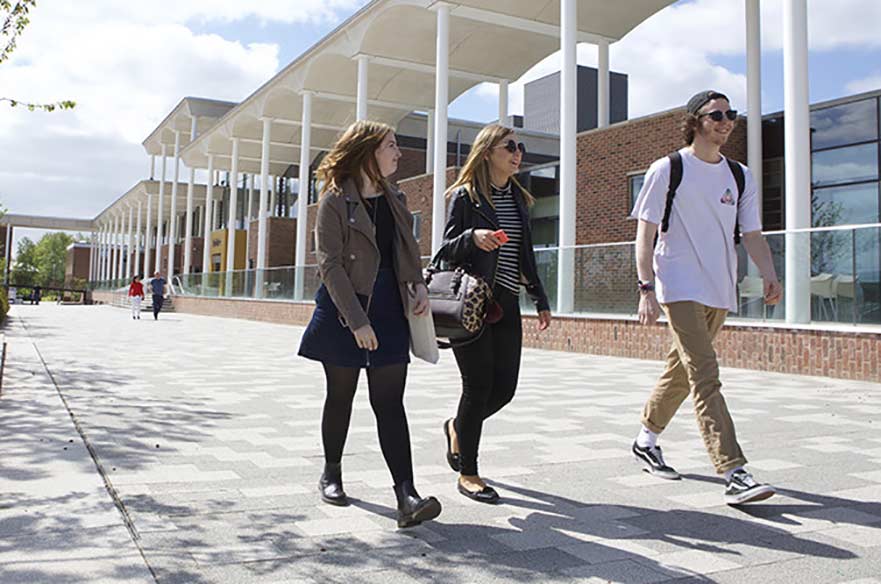 Three students walking past the pavilion