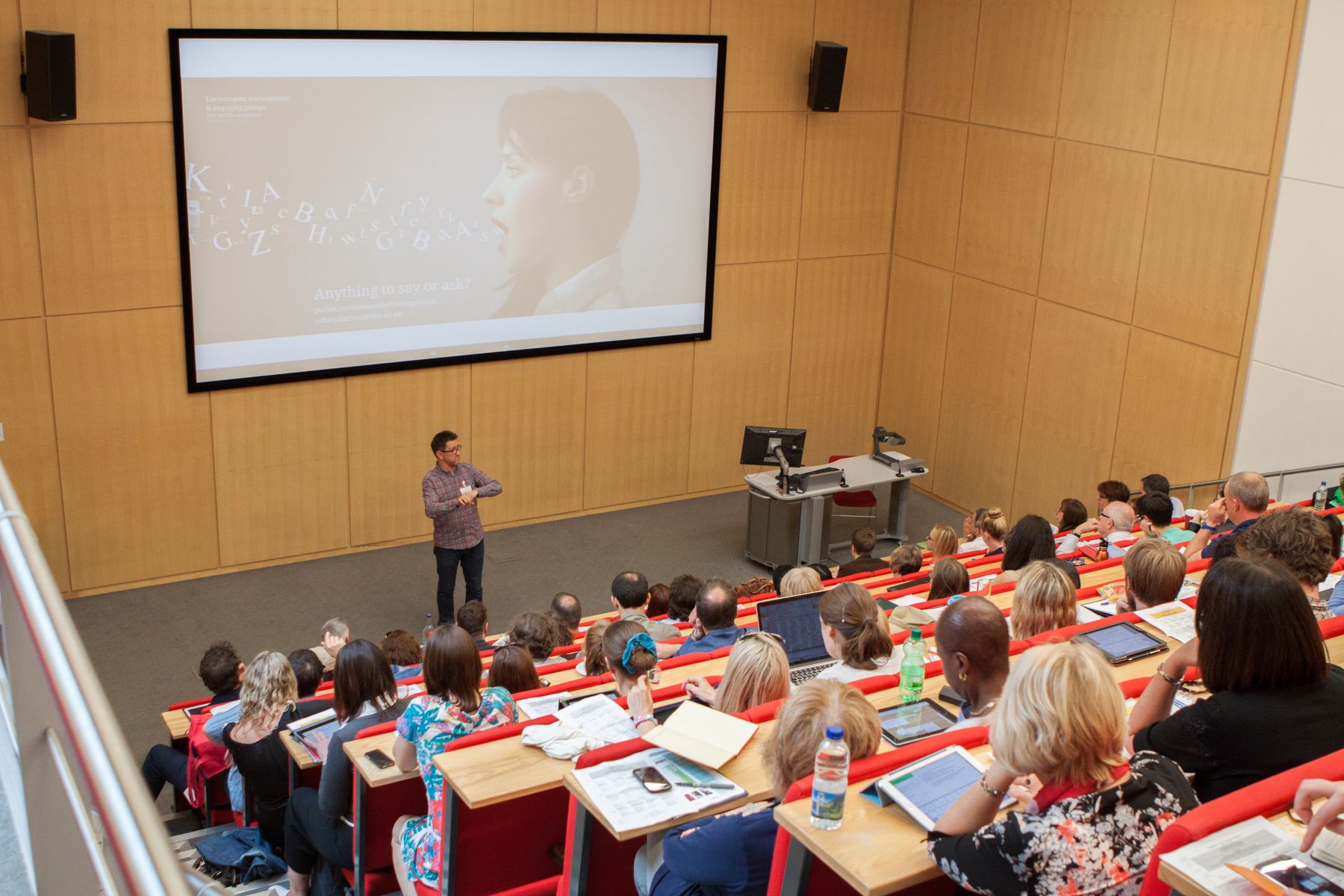 A lecturer talks to a lecture theatre full of people