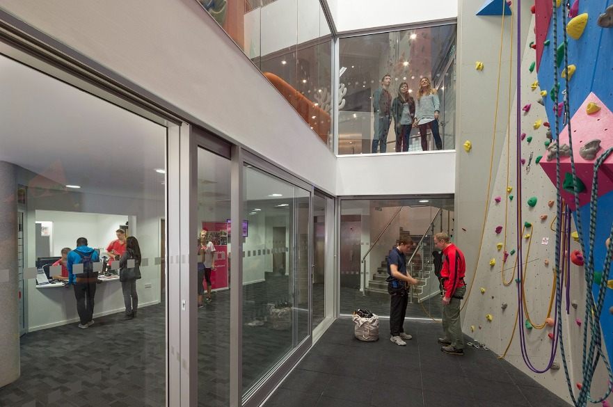 Two people standing in front of the NTSU climbing wall