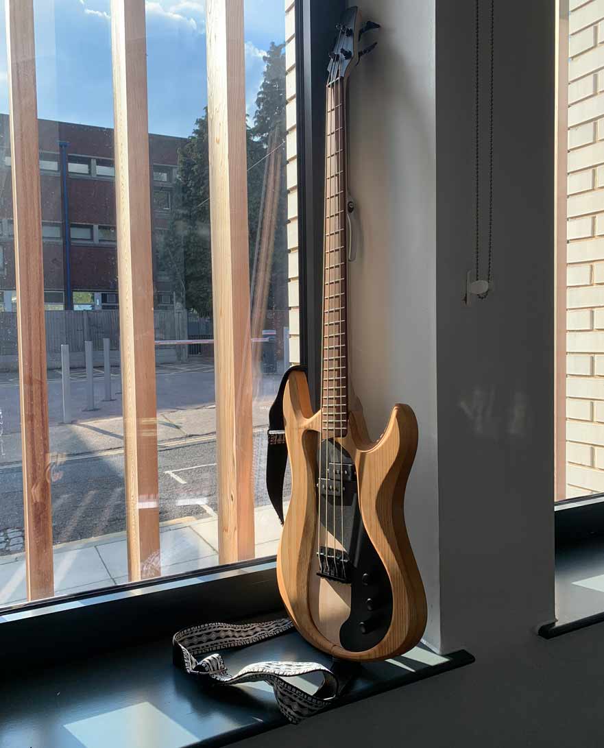 Guitar standing up next to a window