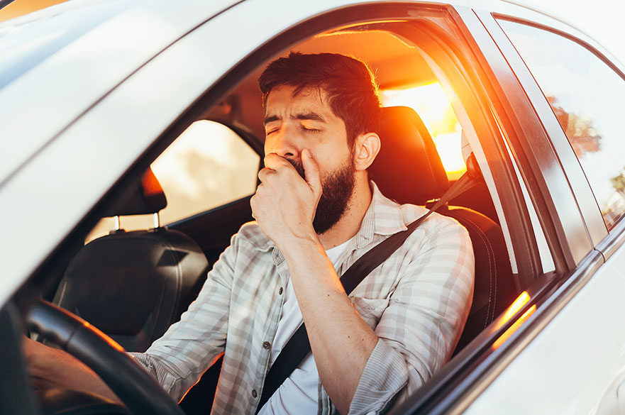 Man yawning while driving a car