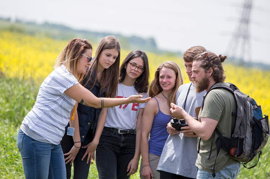 Students outdoors looking at a dragonfly in one of their hands