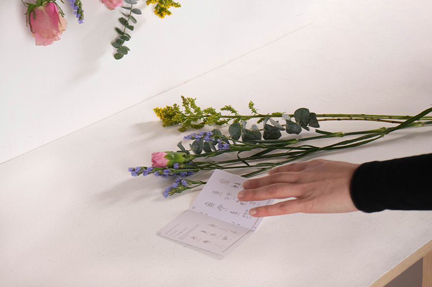 Hand placing instructions next to a bunch of flowers