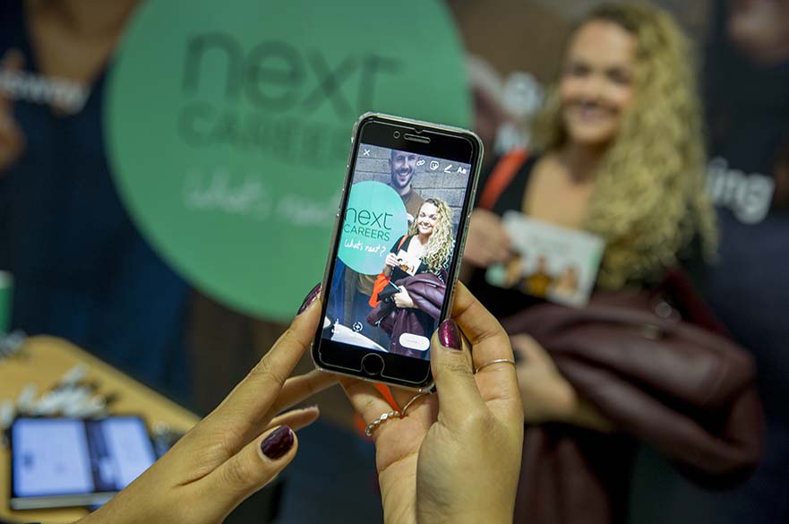 Student with mobile phone at jobs fair
