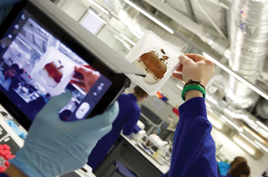 Student taking photo of science experiment with tablet