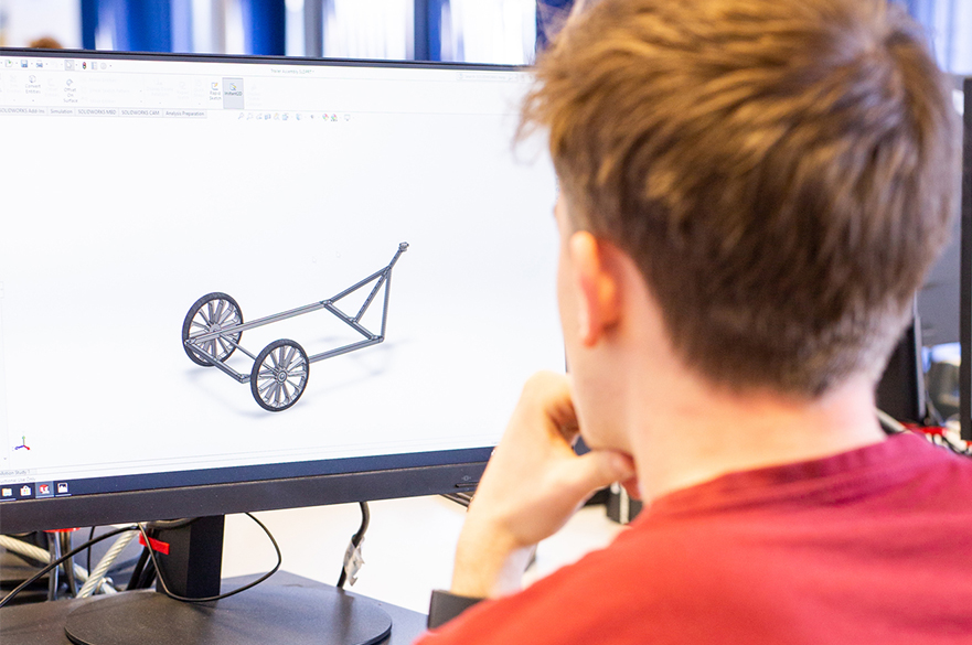 A student looking at a computer screen with a 3d drawing on
