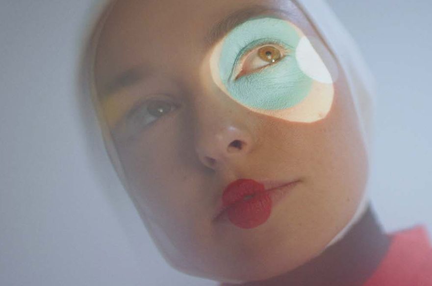 Stella Donnelly staring with red lipstick on and a light shining in one eye.