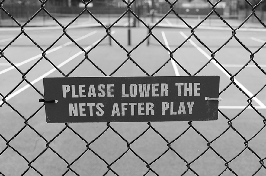 A fence with a sign saying, please lower nets after play.
