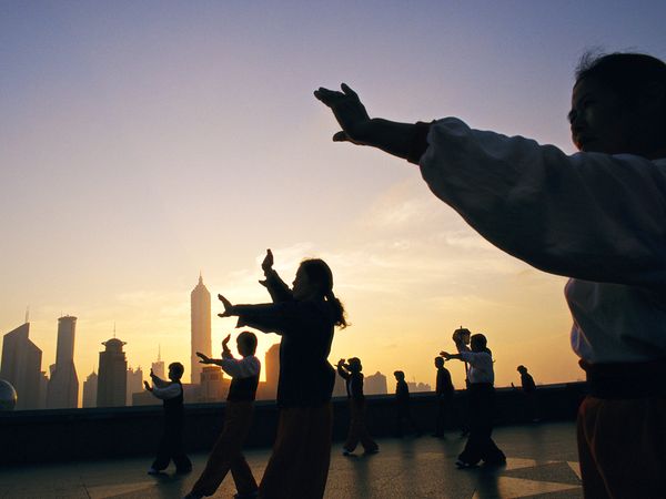 Group doing tai chi on a city rooftop
