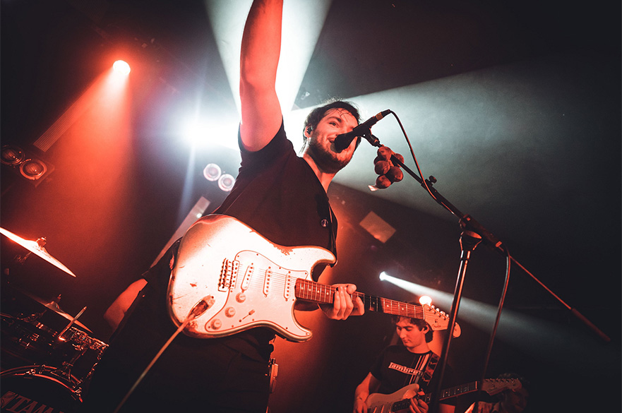 A guitarist performing on stage in front of a mic.