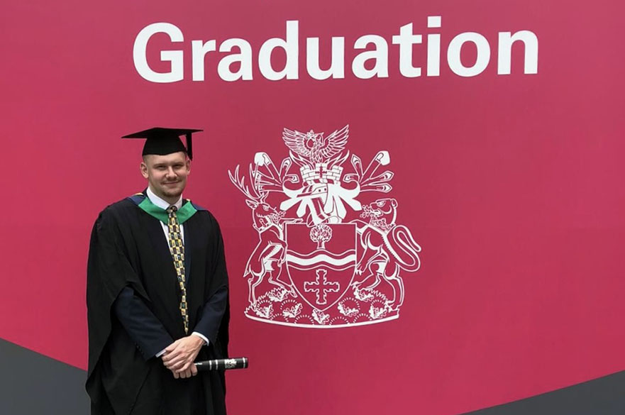 Journalism Graduate Cameron Rutherford celebrates his graduation wearing a gap and gown.