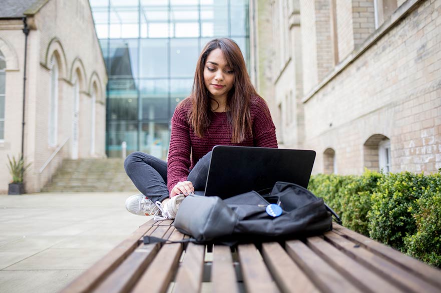 Student using laptop in courtyard