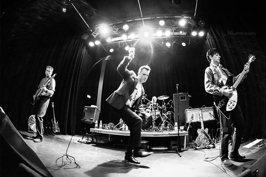 A black and white image of three men performing on stage.