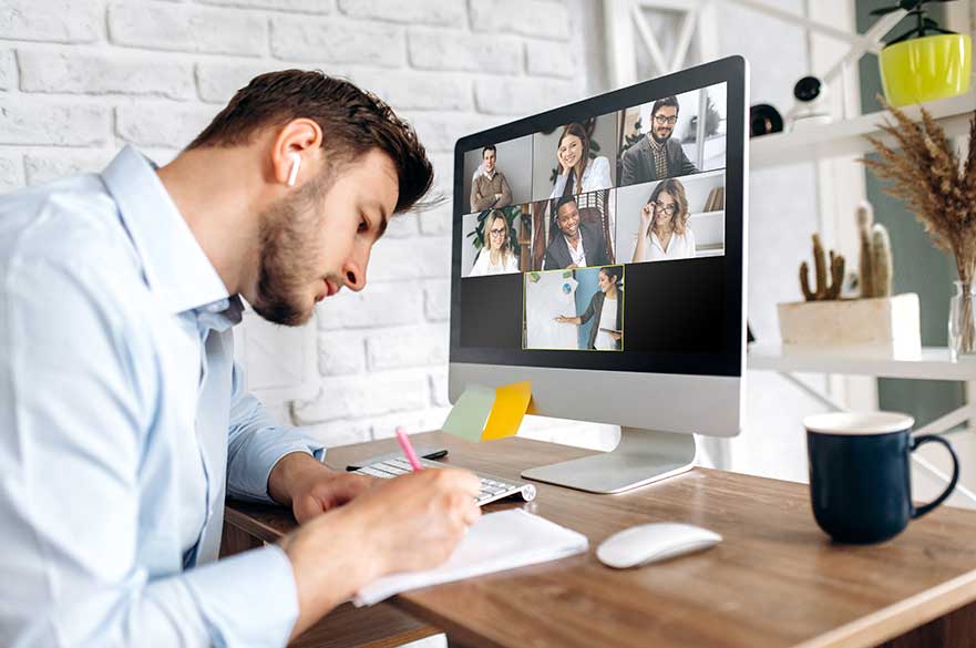 A man takes part in an online learning session with a group of people on his laptop screen