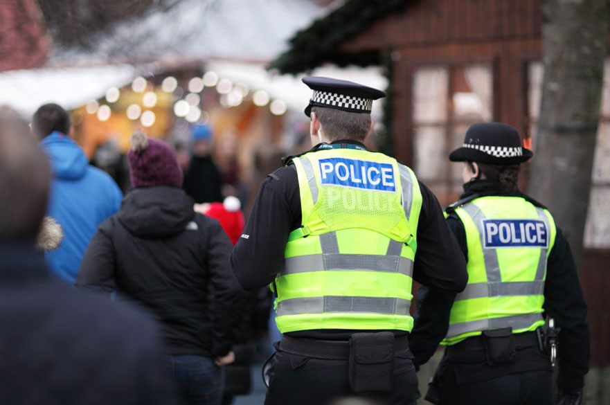 Back view of two British police officers, one male and one female, at an outdoor market