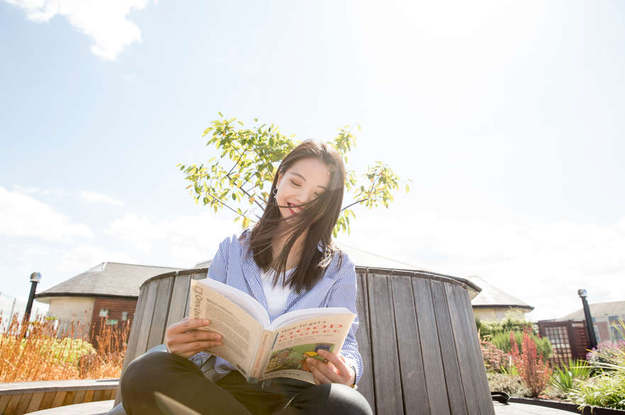 International student reading text book outdoors