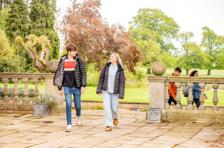 Two students walking along a green space