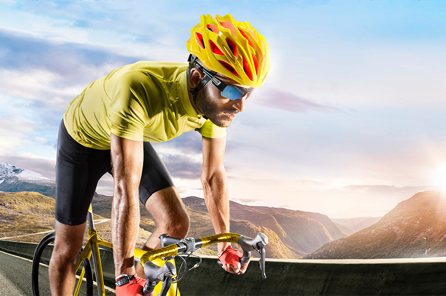 A man with a yellow helmet riding a bike.