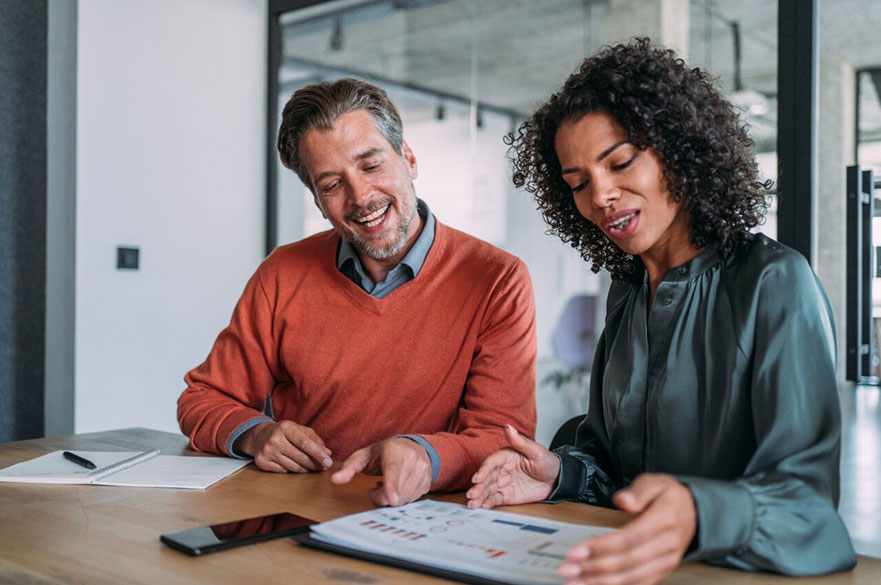 Man and woman sitting at a desk looking at charts