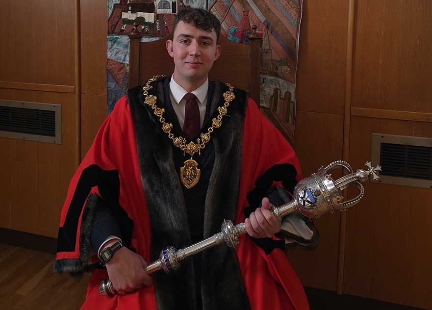 Picture of Harry Atkinson sitting holding a mace with mayoral chains around his neck