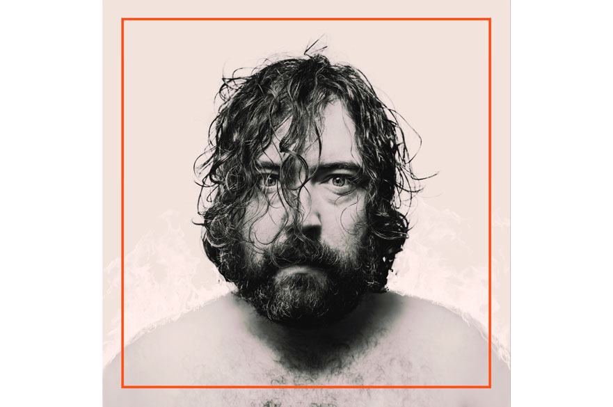 Nick Helm wearing no shirt, head and shoulders looking at the camera.