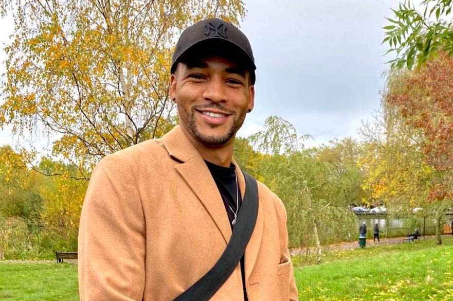 Josh Sharpe smiles at the camera in a park setting