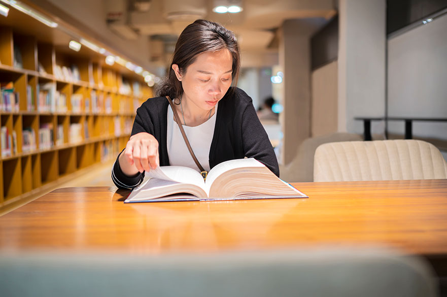 woman reading a book at a library