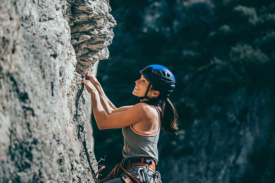 Woman climbing up a rock face