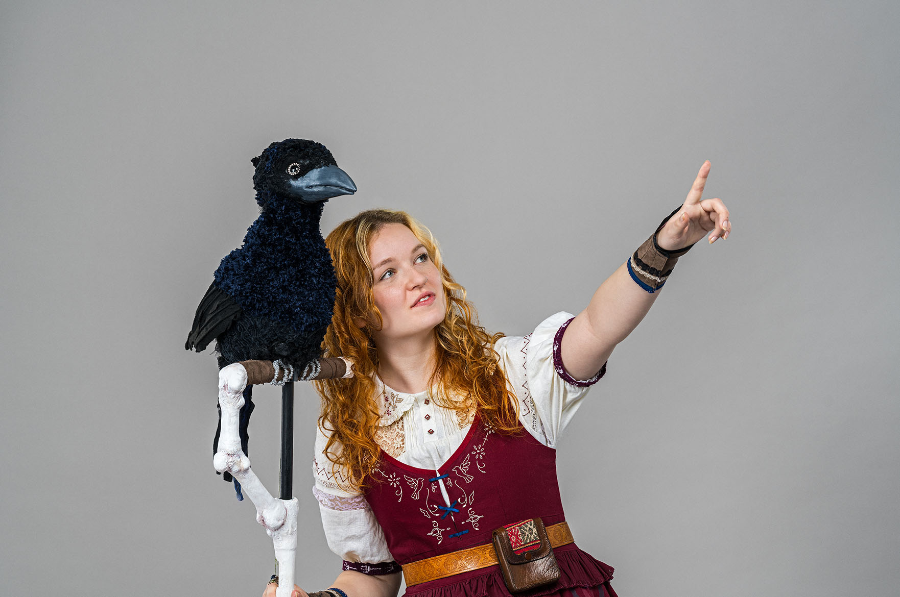 Person wearing a red and white fantasy costume with red and white fantasy costume whislt holding a raven prop