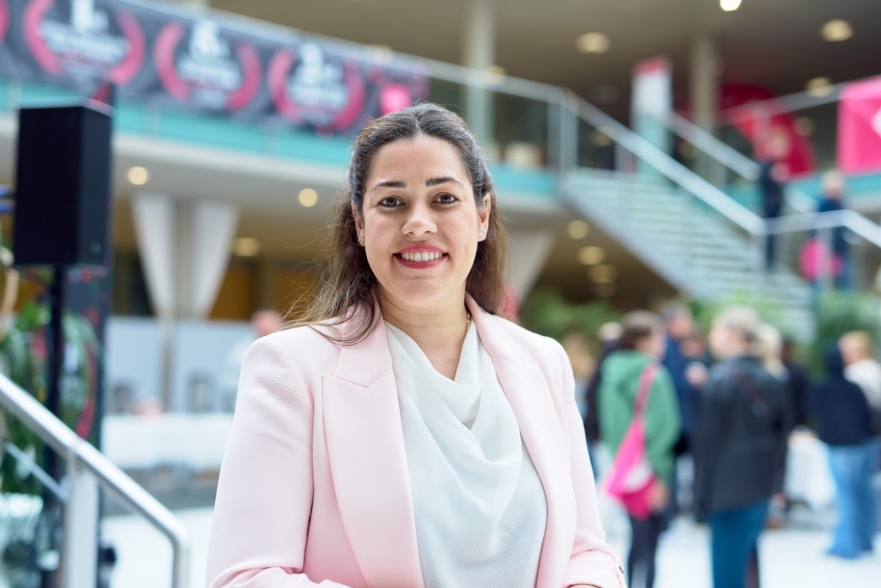 Person smiling at camera in white shirt and pink blazer
