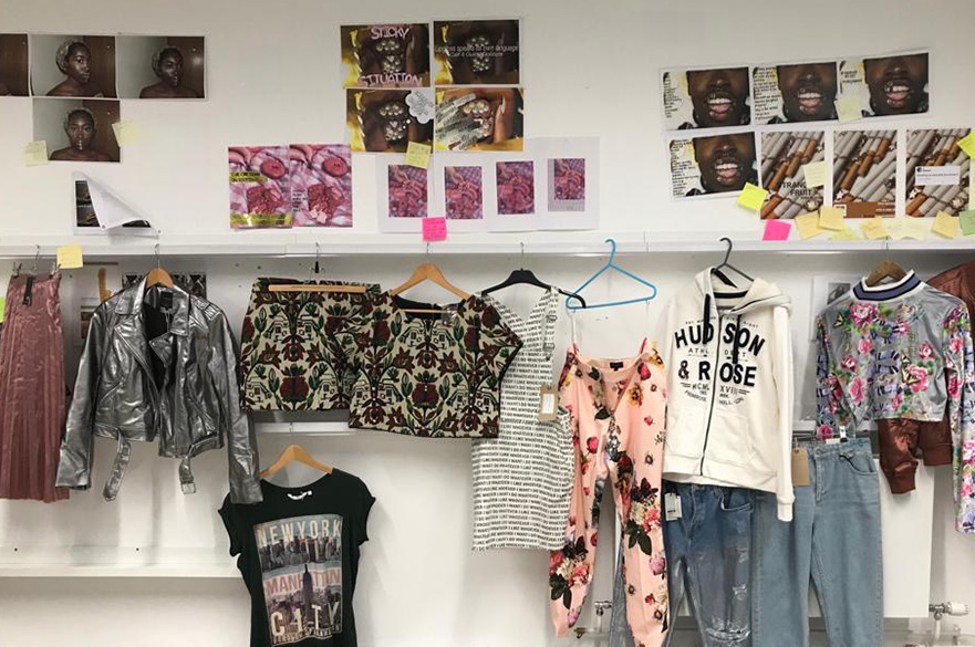 A collection of clothing and pictures on a wall - on shelves and hung up.