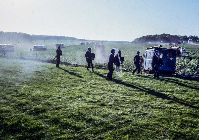 Police with riot shields walking in a field
