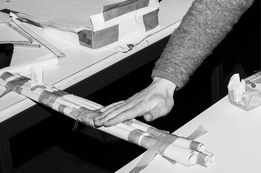 A black and white image of a pair of hands rolling paper wrapped in tape.