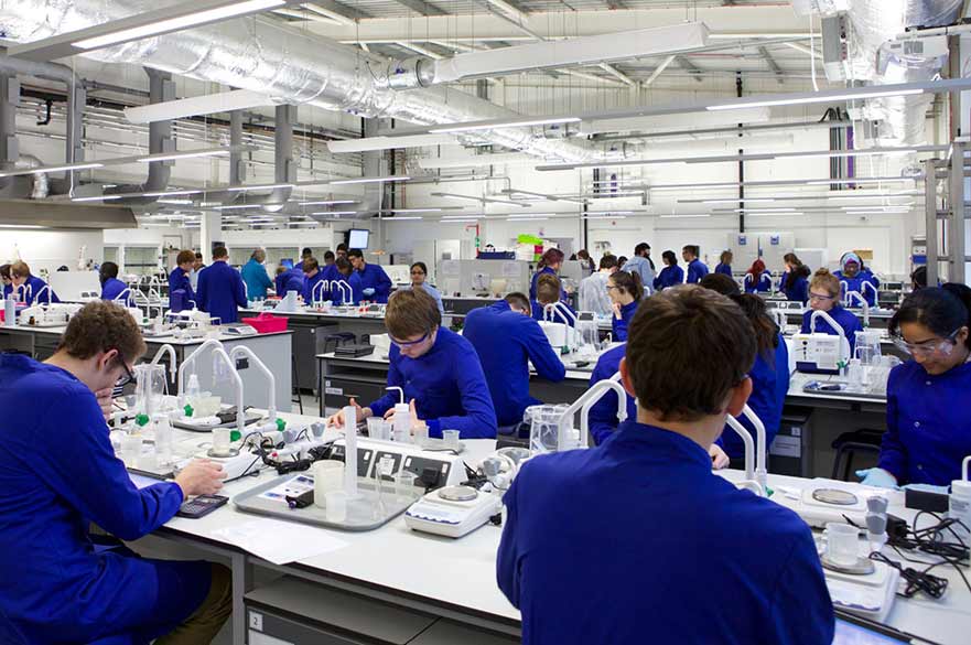 lab full of students working in blue lab coats